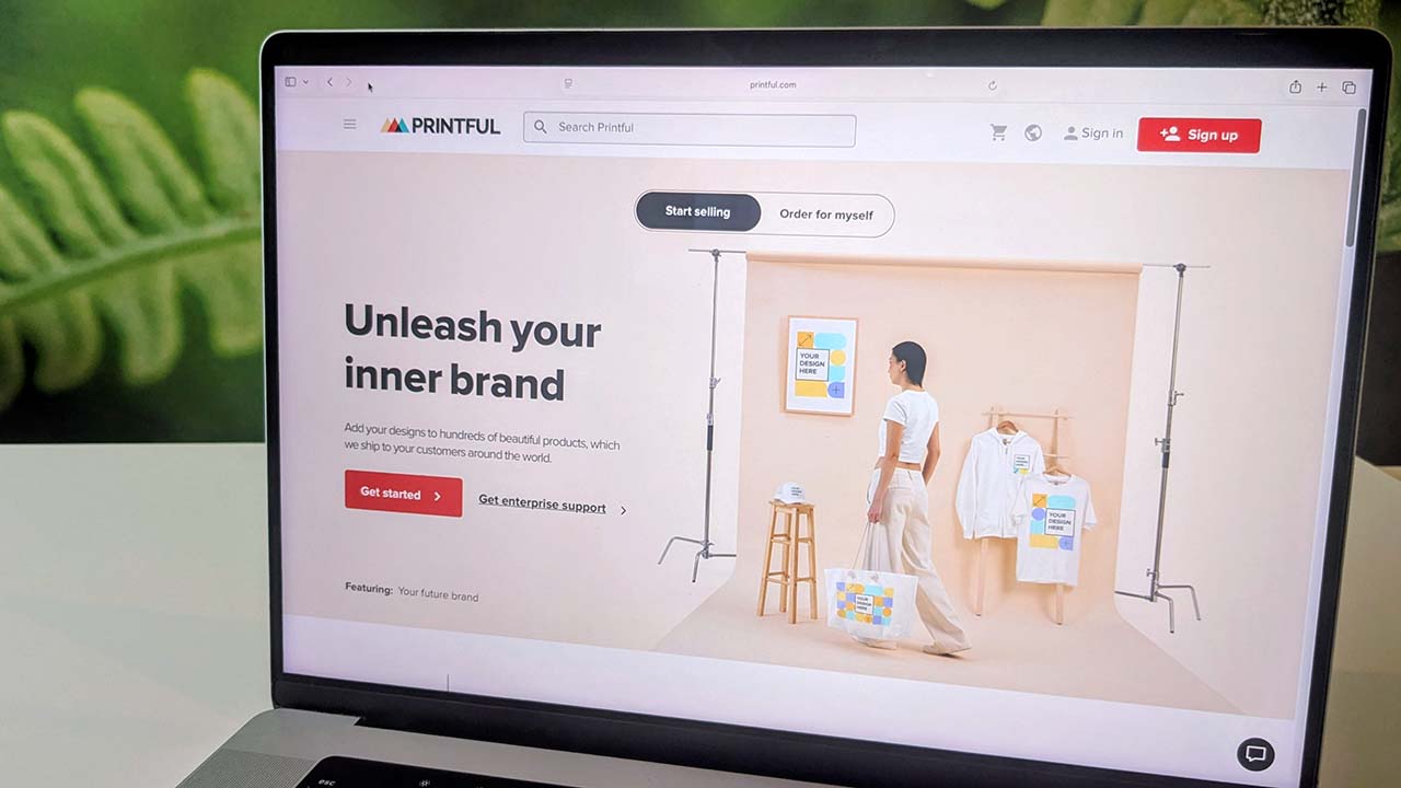 A photo of a laptop with the Printful website open on the screen.